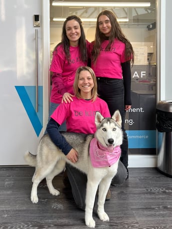 three women wearing hot pink shirts that say be kind and a husky smile for a photo in front of the Arctic Leaf office